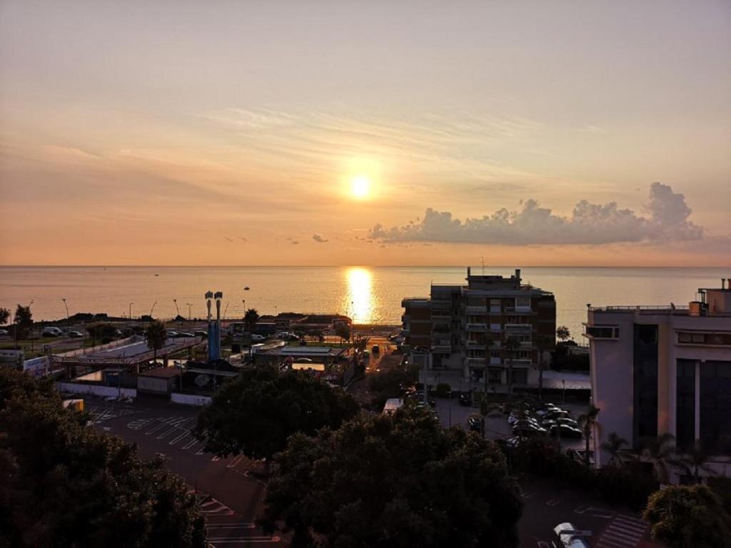 a view of a city with the sun setting over the water at Venere B&B in Catania