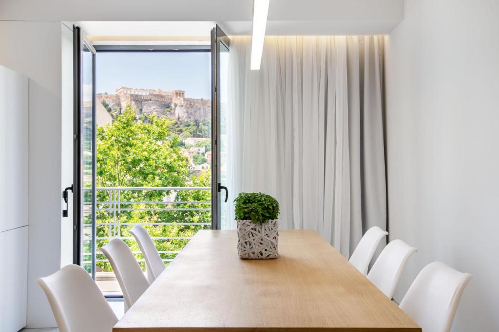 uma sala de jantar com mesa e cadeiras e uma grande janela em NS PLACE Modern Apartment Acropolis view em Atenas