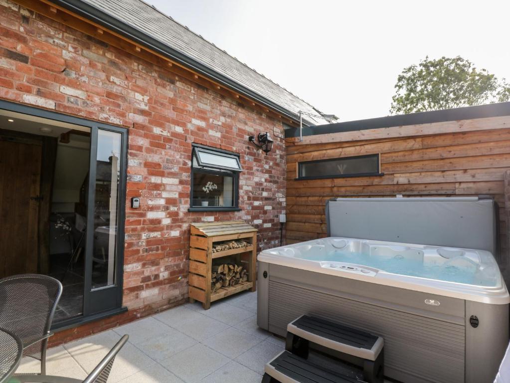 a hot tub on a patio next to a brick building at The Piggery in Hereford