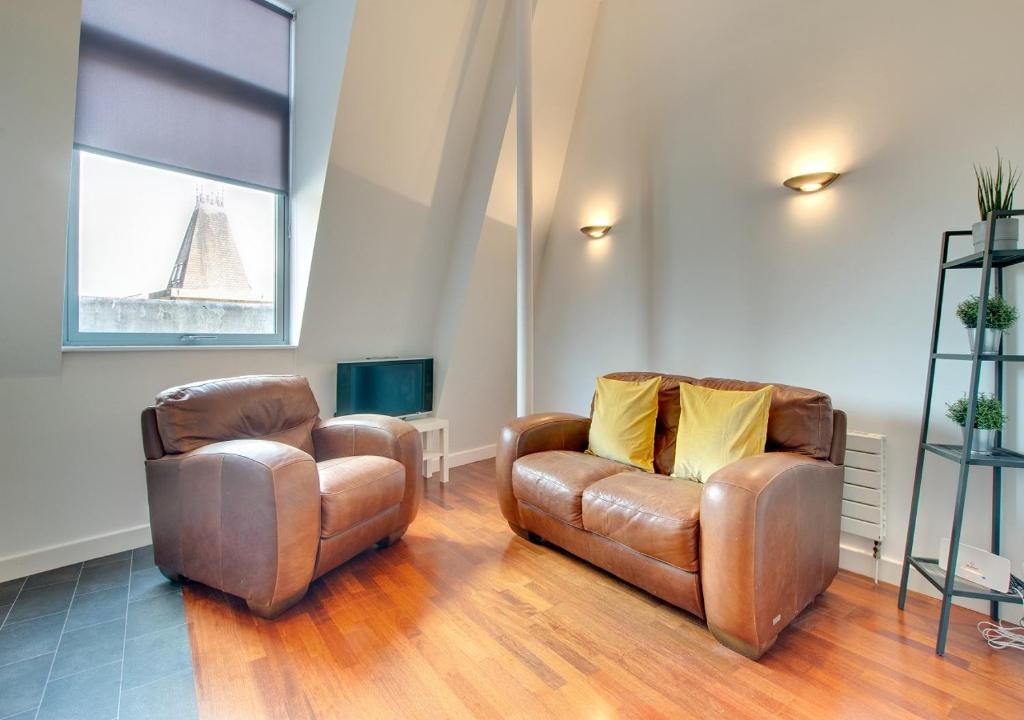 sala de estar con 2 sillas de cuero y TV en Crown Apartments 511 by Week2Week en Newcastle