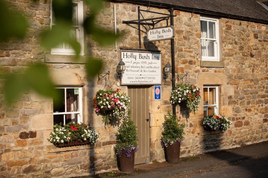 a stone building with flower pots on the front of it at Hollybush Inn in Greenhaugh