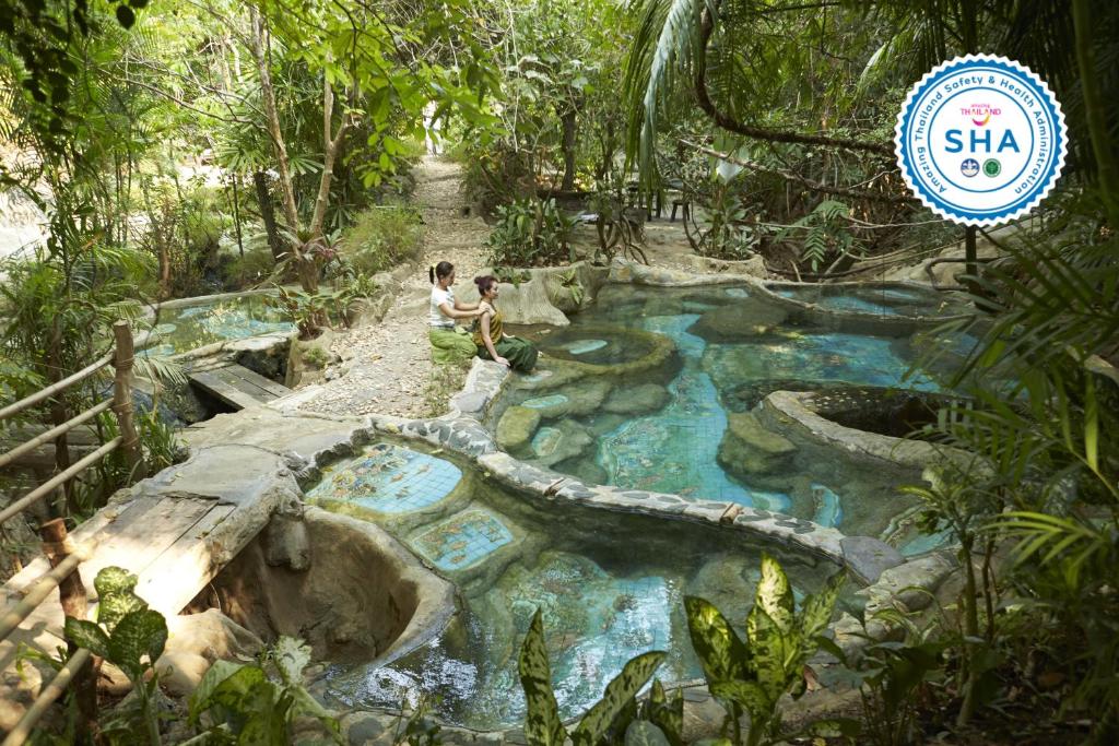 a man and a woman standing in front of a pool of water at Wareerak Hot Spring & Wellness- SHA Extra Plus in Khlong Thom