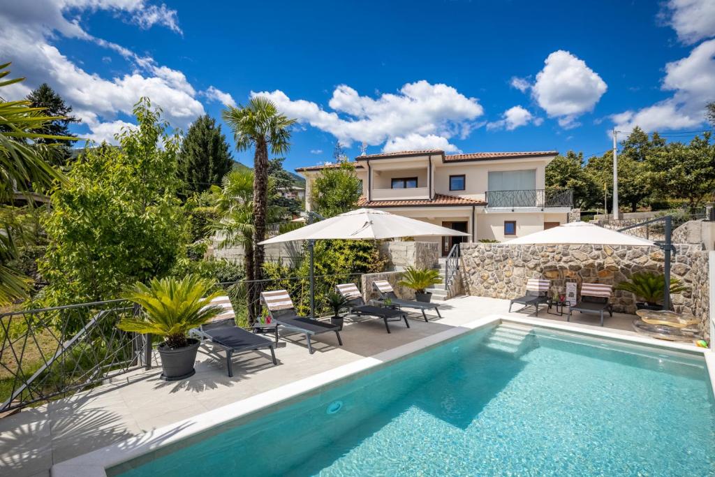 une villa avec une piscine dotée de chaises et de parasols dans l'établissement Villa SaLu, à Opatija