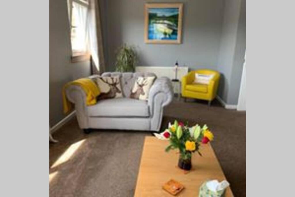 a living room with a couch and a table at Creag Mhor Self Catering Holiday Apartment in Aberfoyle