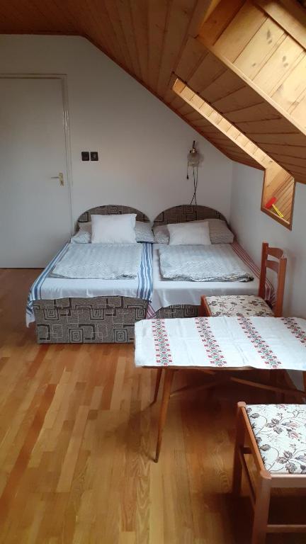 a room with two beds and a table in it at Anna vendégház in Balatonakali