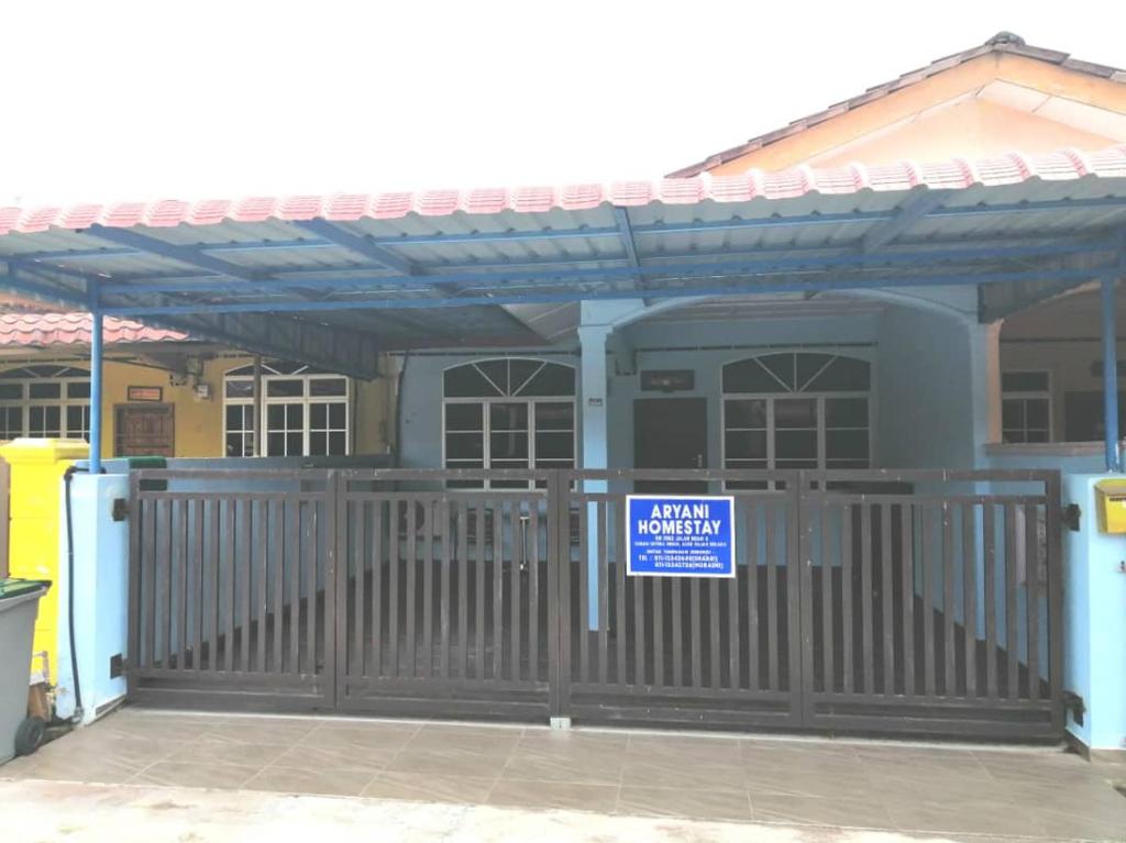 um edifício com um portão com um sinal em Aryani Homestay em Kampong Kelemak