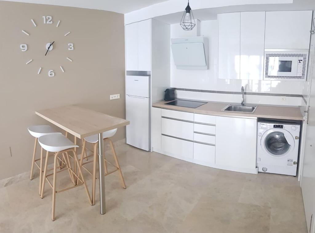 kuchnia z białymi szafkami, stołem i zegarem w obiekcie Stylish apartment in Portofino, near the beach and bars w Almerimar