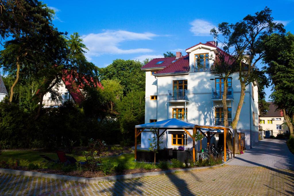 una casa blanca con una tienda azul delante de ella en Willa Pod Lipami, en Świnoujście