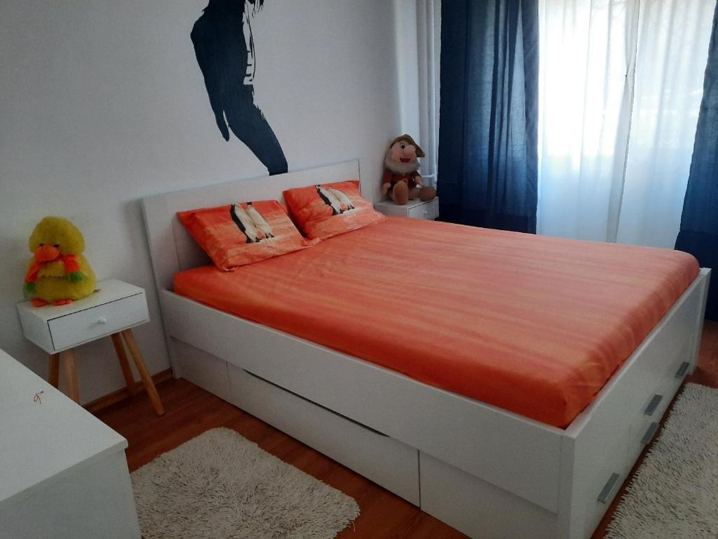 a bedroom with a bed with orange sheets and stuffed animals at Serghi in Mangalia