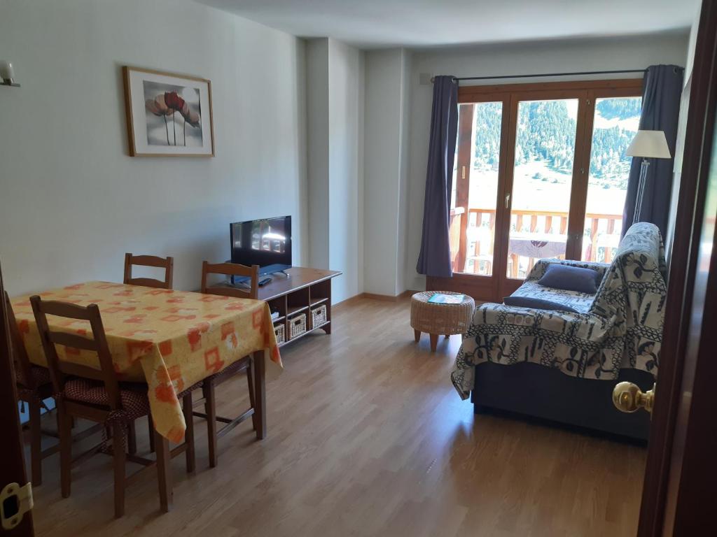 sala de estar con mesa y silla en Terrasses- Vacances Pirinenca, en El Tarter