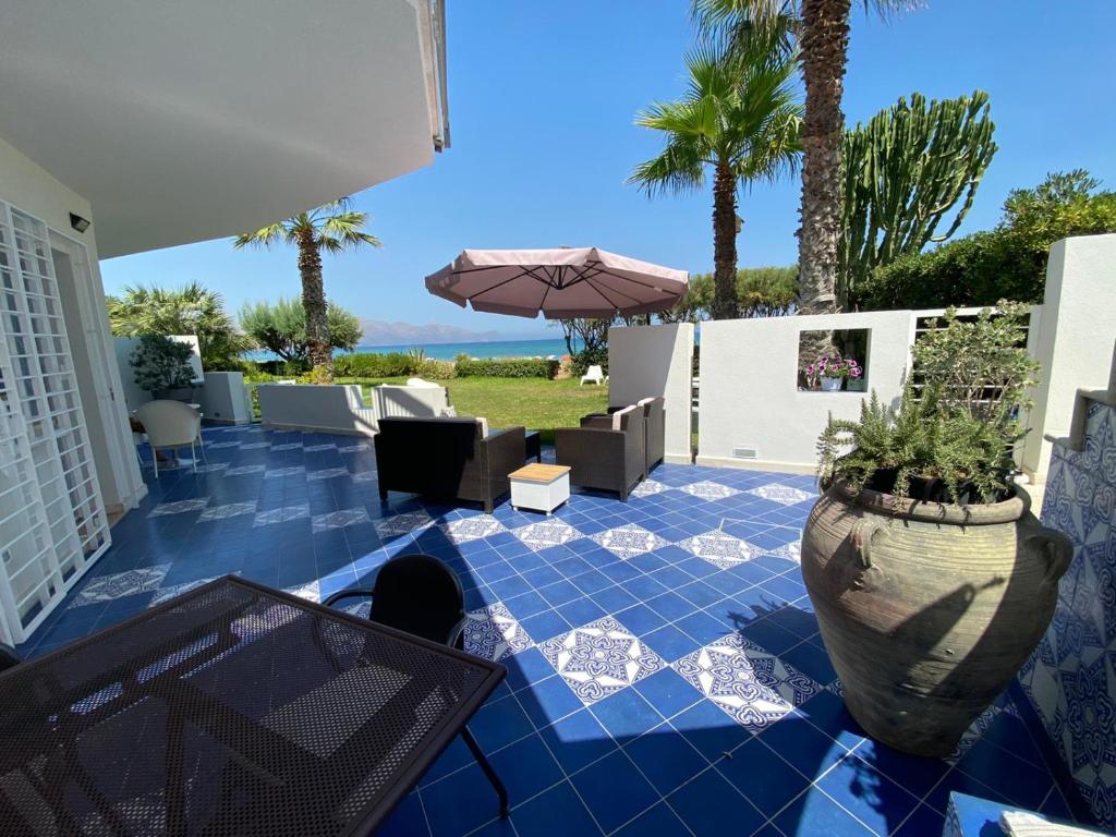 eine Terrasse mit einem Tisch, einem Sonnenschirm und Palmen in der Unterkunft Casa Vacanze Ibiscus in Alcamo Marina