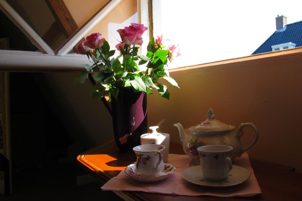 einen Tisch mit einer Vase Blumen und zwei Tassen in der Unterkunft Wild Roses in Amsterdam