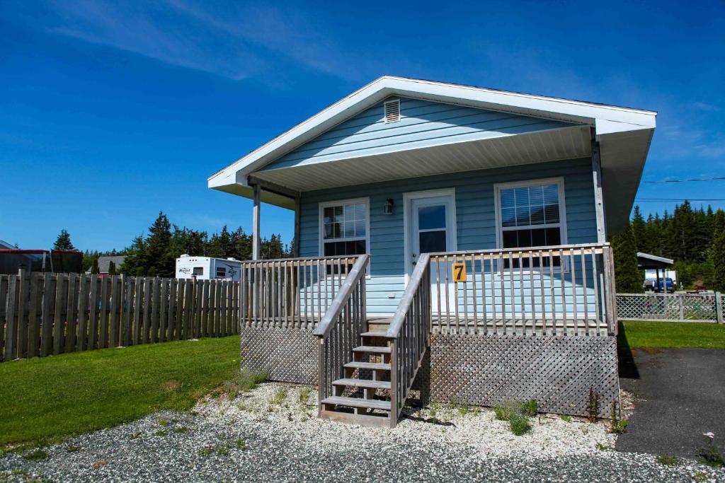 une petite maison bleue avec une clôture en bois dans l'établissement Peck's Housekeeping Cottages, à Louisbourg