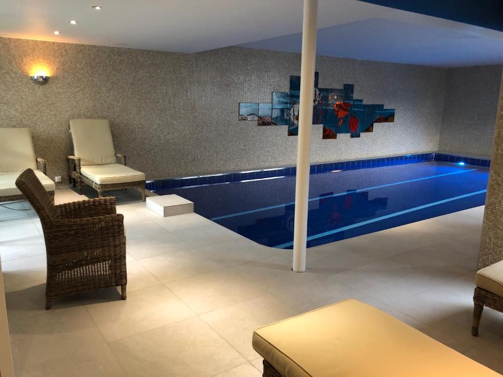 a swimming pool in a room with chairs and a table at Hotel Scherf Residenz in Bad Lippspringe