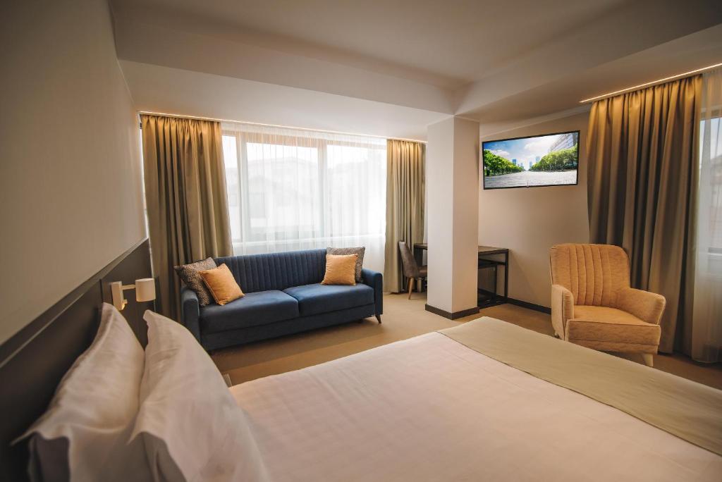 une chambre d'hôtel avec un lit et un canapé dans l'établissement NOVO Boutique, à Râmnicu Vâlcea