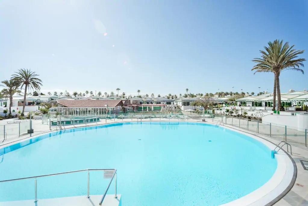 a large swimming pool at a resort with palm trees at Bungalow con piscina Maspalomas in Maspalomas