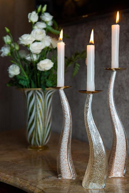 two silver candle holders on a table with a vase of flowers at Domus Superior in Venice