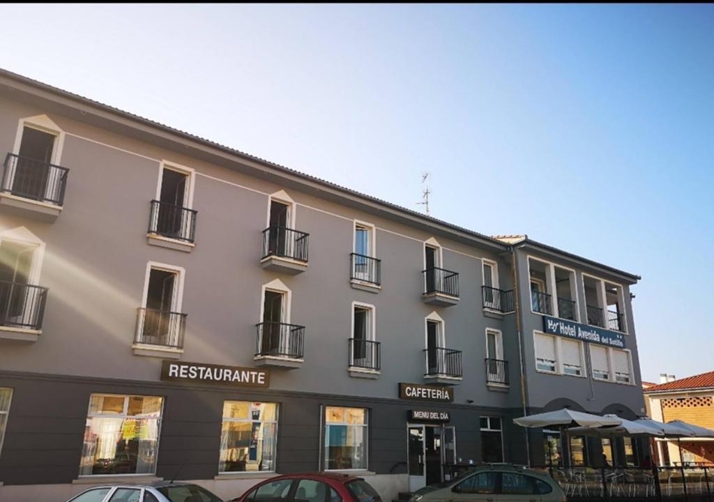 un gran edificio con coches estacionados frente a él en Hotel Avenida del Sotillo, en La Lastrilla