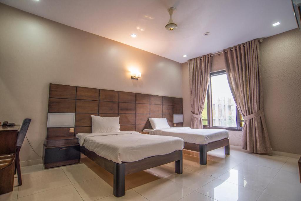 pokój hotelowy z 2 łóżkami i oknem w obiekcie Hillside Homes w mieście Karaczi