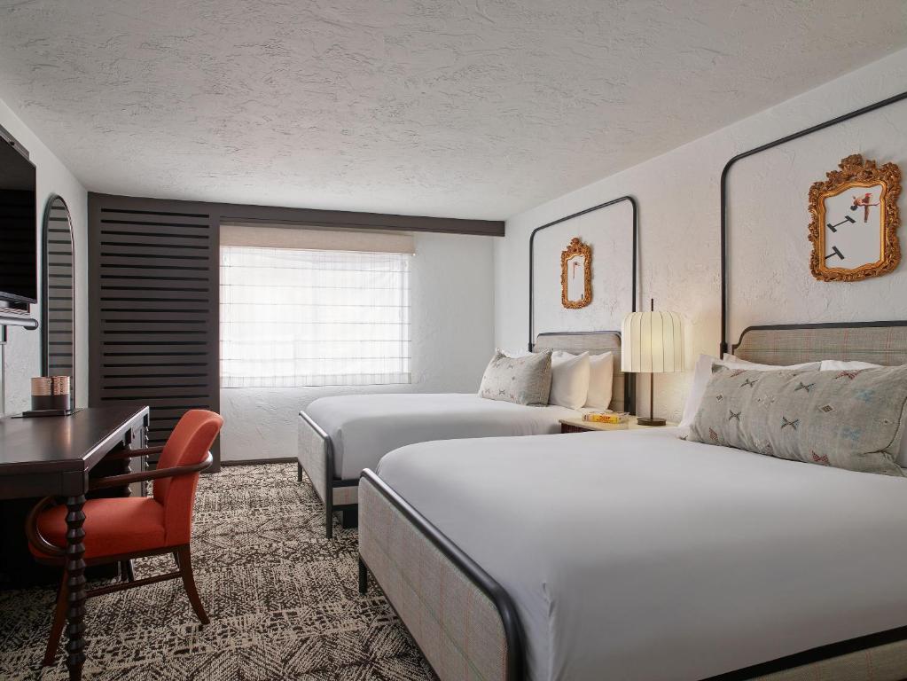 a hotel room with two beds and a desk at Palmoro House in Santa Barbara