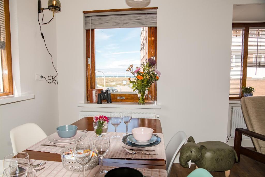 een eetkamer met een tafel en een raam bij Emma's beach house in Katwijk aan Zee