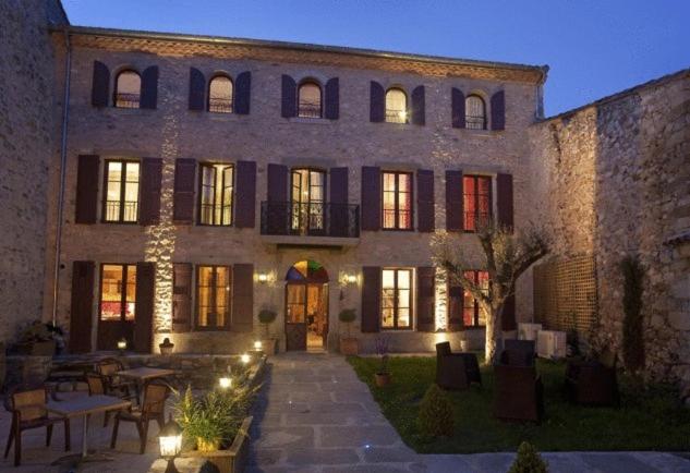 a large stone building with tables and chairs in front of it at Bed & Breakfast Demeure du Pareur in Villeneuve-Minervois