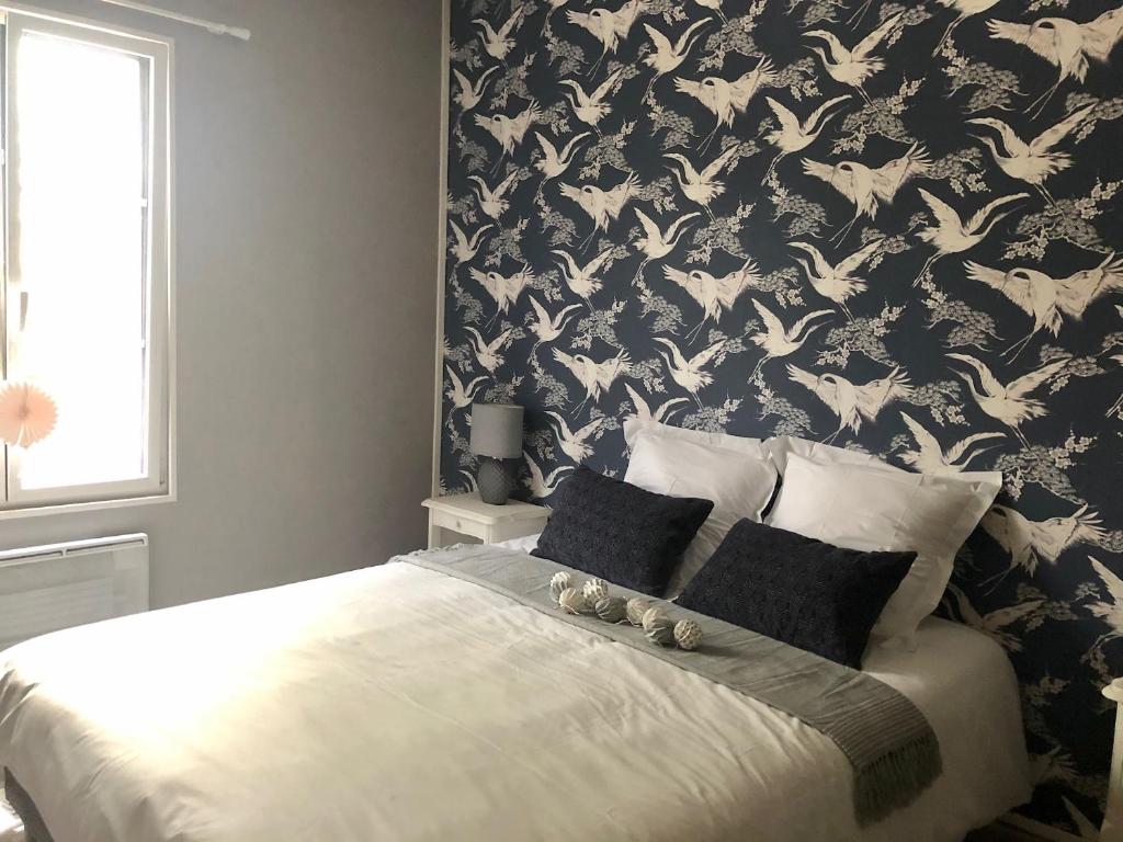 Schlafzimmer mit einem Bett mit einer schwarz-weißen Tapete in der Unterkunft Le charme et l’original in Ailly-le-Haut-Clocher