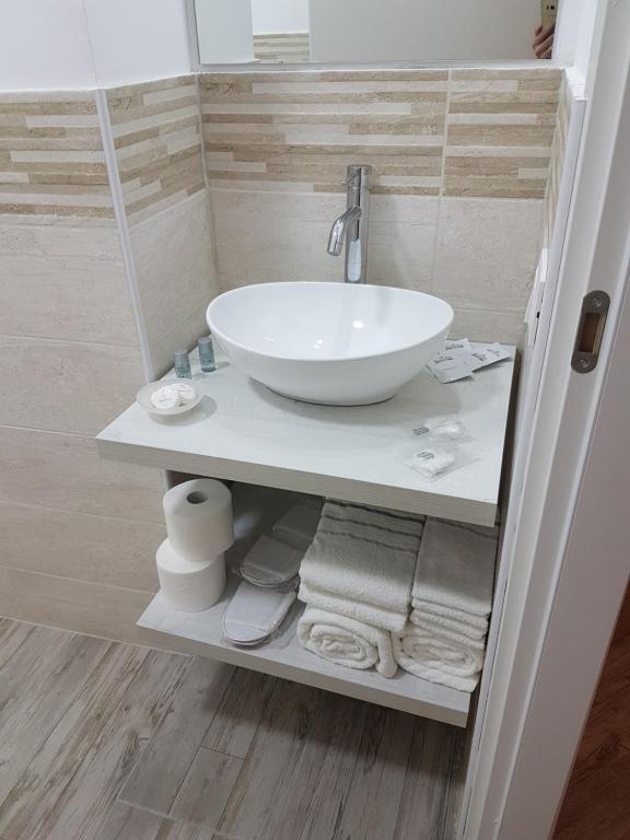 a bathroom with a white sink and towels on a shelf at Giuchry Apartment in Merano