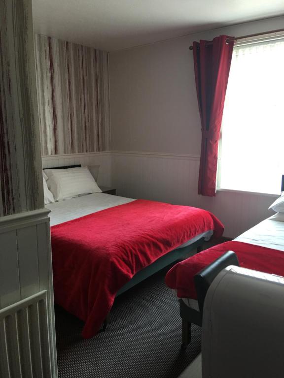 um quarto com uma cama com um cobertor vermelho e uma janela em Kingscliff em Blackpool