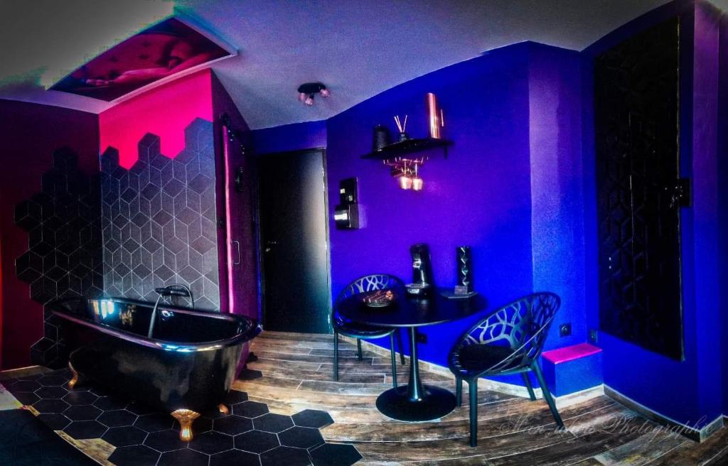 a purple bathroom with a tub and a table and chairs at La Magie d'une Nuit in Agde