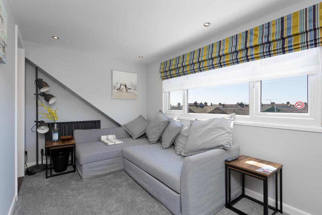 uma sala de estar com um sofá cinzento e uma janela em Stopover at ORCHARD LOFT, cosy and convenient em Portsmouth