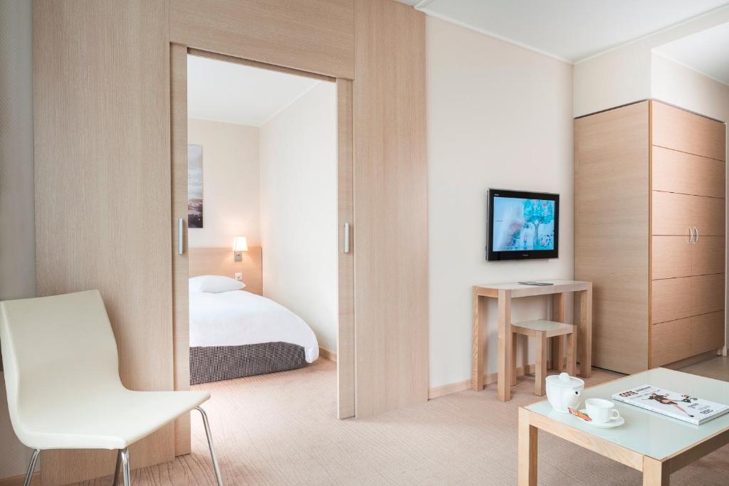 um quarto de hotel com uma cama e um espelho em Starling Hôtel Résidence Genève em Genebra