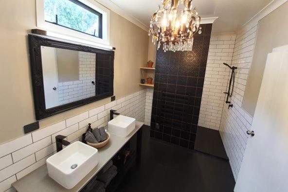 a bathroom with two sinks and a mirror and a chandelier at Sunny Brae Cottages in Tauranga