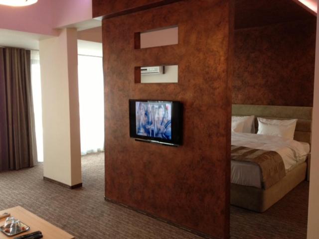 a hotel room with a bed and a tv on a wall at CITY HOTEL & LOUNGE in Slatina