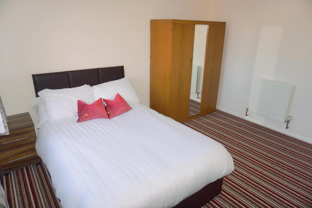 a bedroom with a white bed with two red pillows at The Harvest 2 in Canterbury