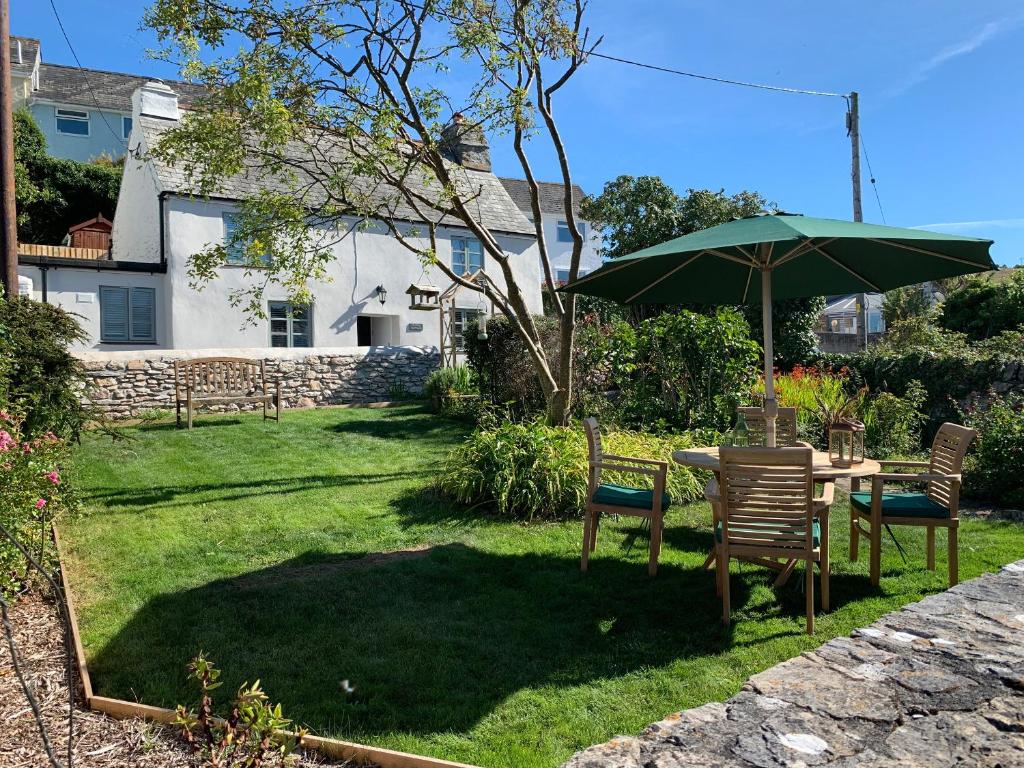 a table and chairs with an umbrella in a yard at Clover Cottage in Plymouth