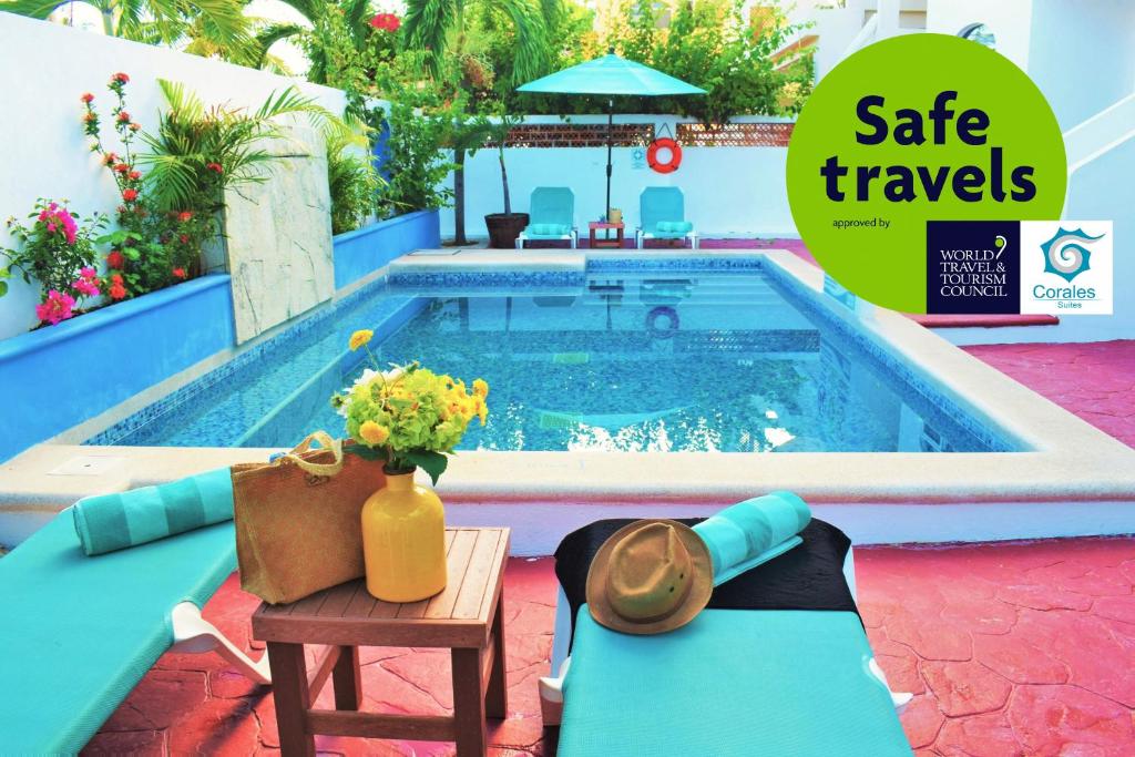 a pool with a table with a vase of flowers next to it at Corales Suites in Puerto Morelos