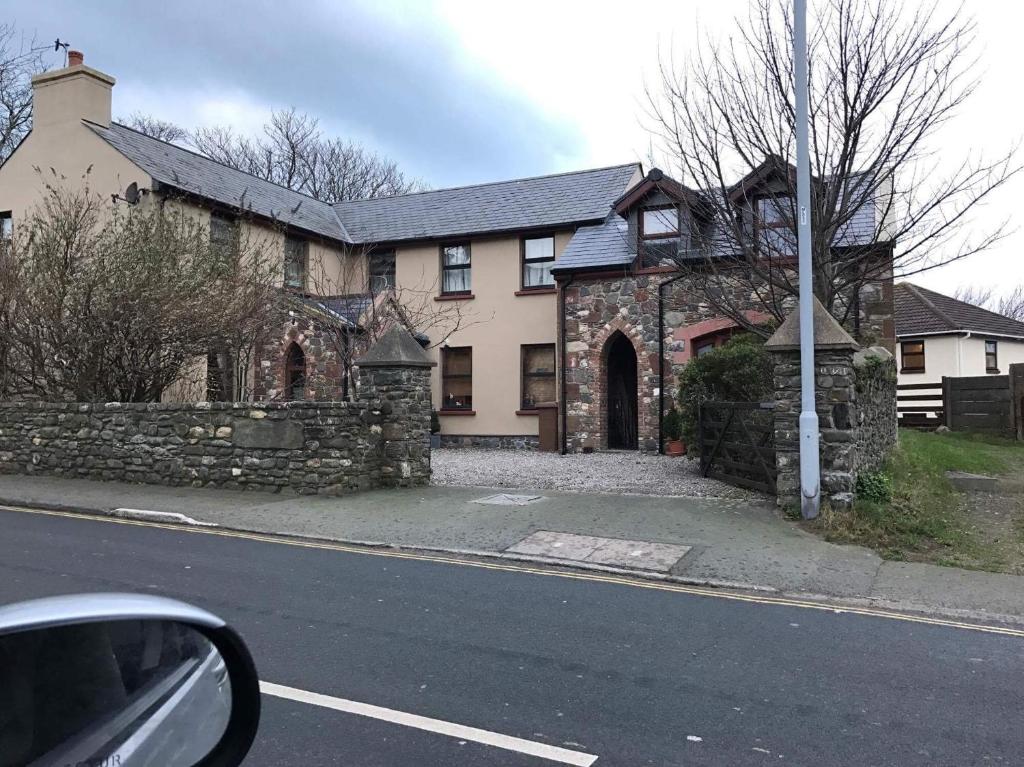 uma velha casa de pedra ao lado de uma rua em Reayrt Ny Marrey em Kirkmichael