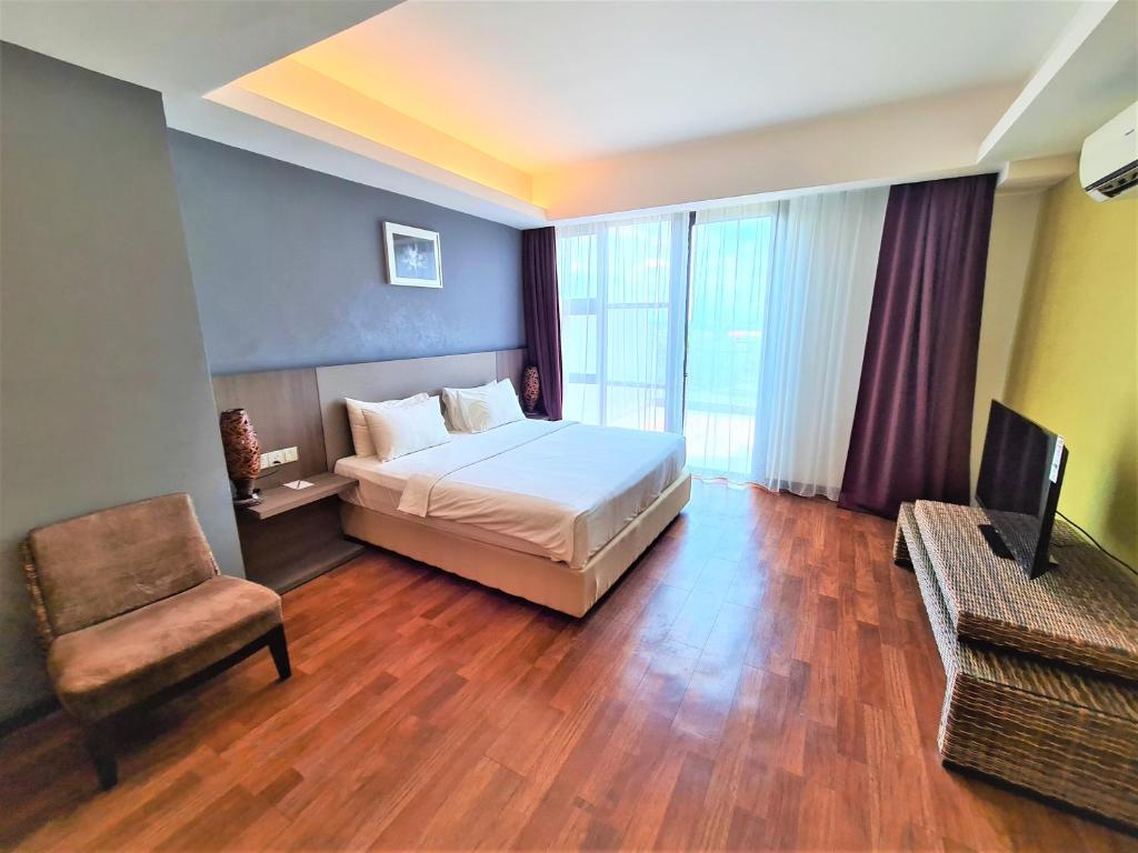 a bedroom with a bed and a chair and a television at Nexus Regency Suites & Hotel in Subang Jaya
