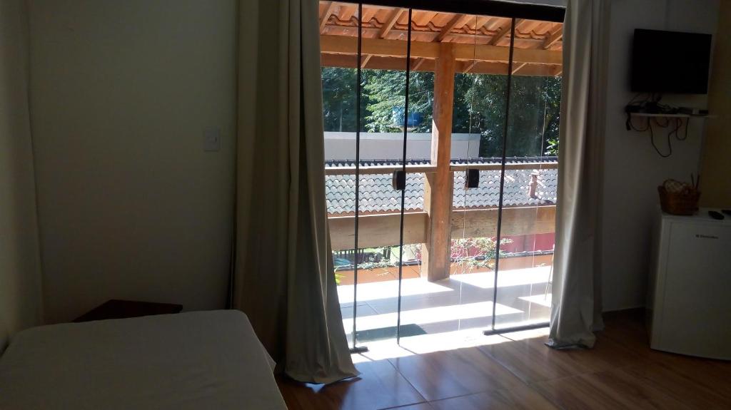 a bedroom with a window with a view of a courtyard at Pousada do Bote - Apart Suítes em " Sítio Santa Helena" , próximo ao Sana in Casimiro de Abreu