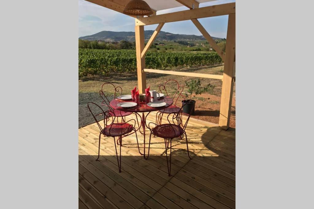 a table and chairs on a porch with a view of a vineyard at La bohème, gîte de charme in Quincié-en-Beaujolais