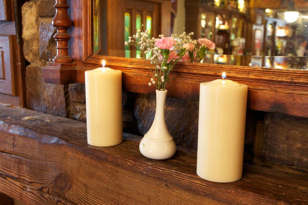 three candles and a vase with flowers on a counter at Leens Hotel in Abbeyfeale