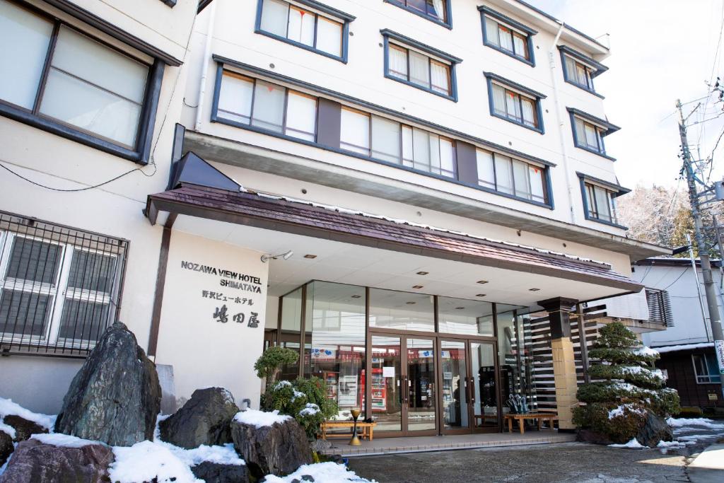 Nozawa View Hotel Shimataya في نوزاوا أونسن: متجر أمام مبنى به ثلج