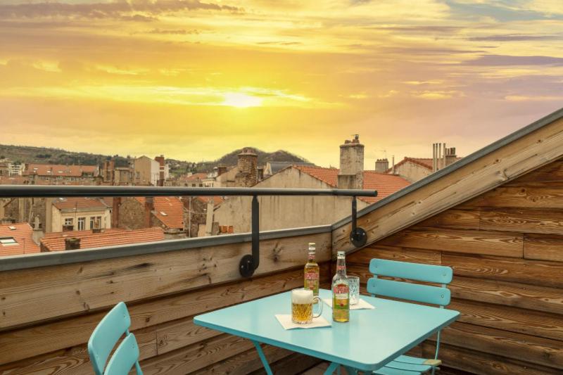 a table and chairs on a balcony with a view at Urban Style, Hôtel Le Cheval Noir, Saint-Étienne in Saint-Étienne