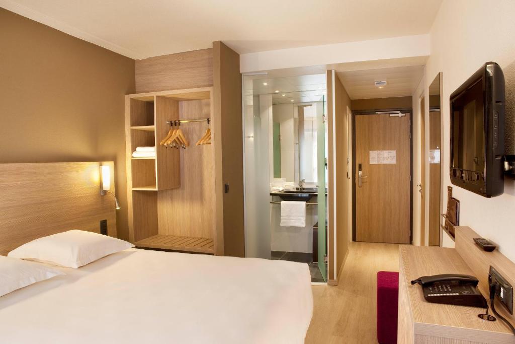 a bedroom with a white bed and a bathroom at Escale Oceania Quimper Centre in Quimper