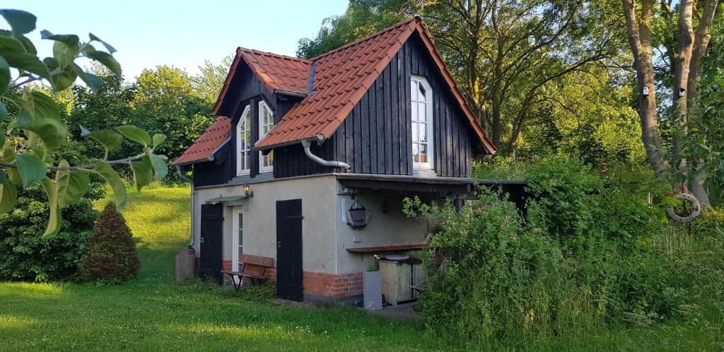 una pequeña casa en blanco y negro con techo rojo en Niedliches-kleines-Ferienhaeuschen-auf-Ruegen-nahe-Stralsund, en Altefähr