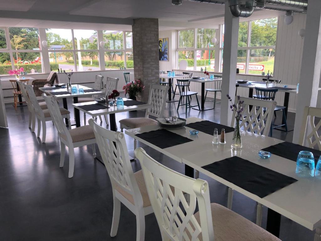 a restaurant with white tables and white chairs and windows at Samsted in Middelfart