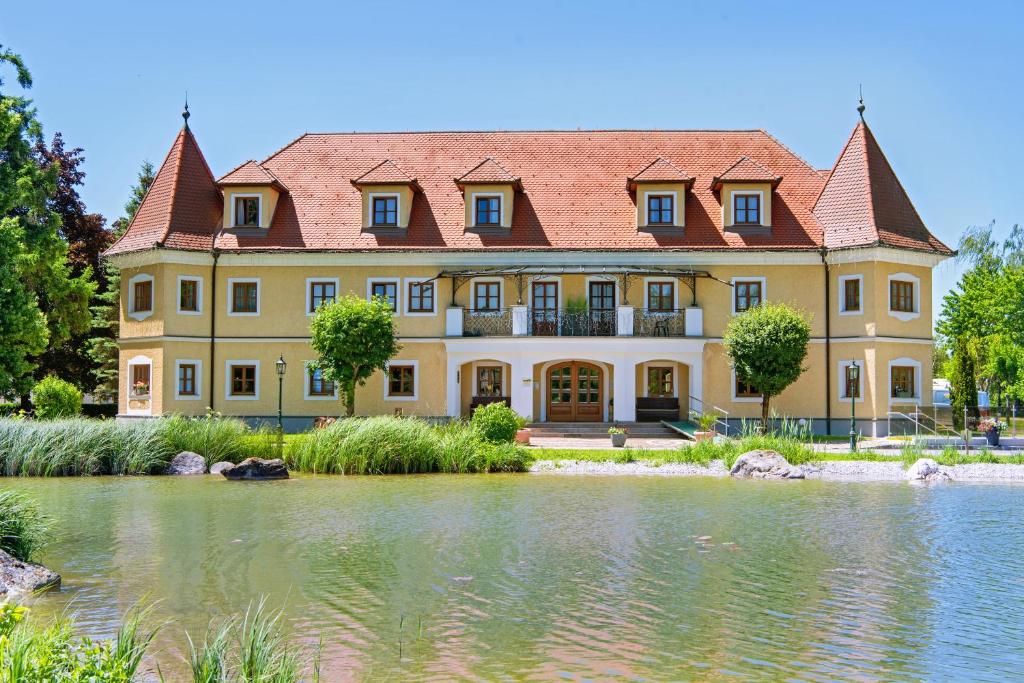 ein großes gelbes Haus mit einem Teich davor in der Unterkunft Almtalhotel Appartements in Pettenbach in Pettenbach