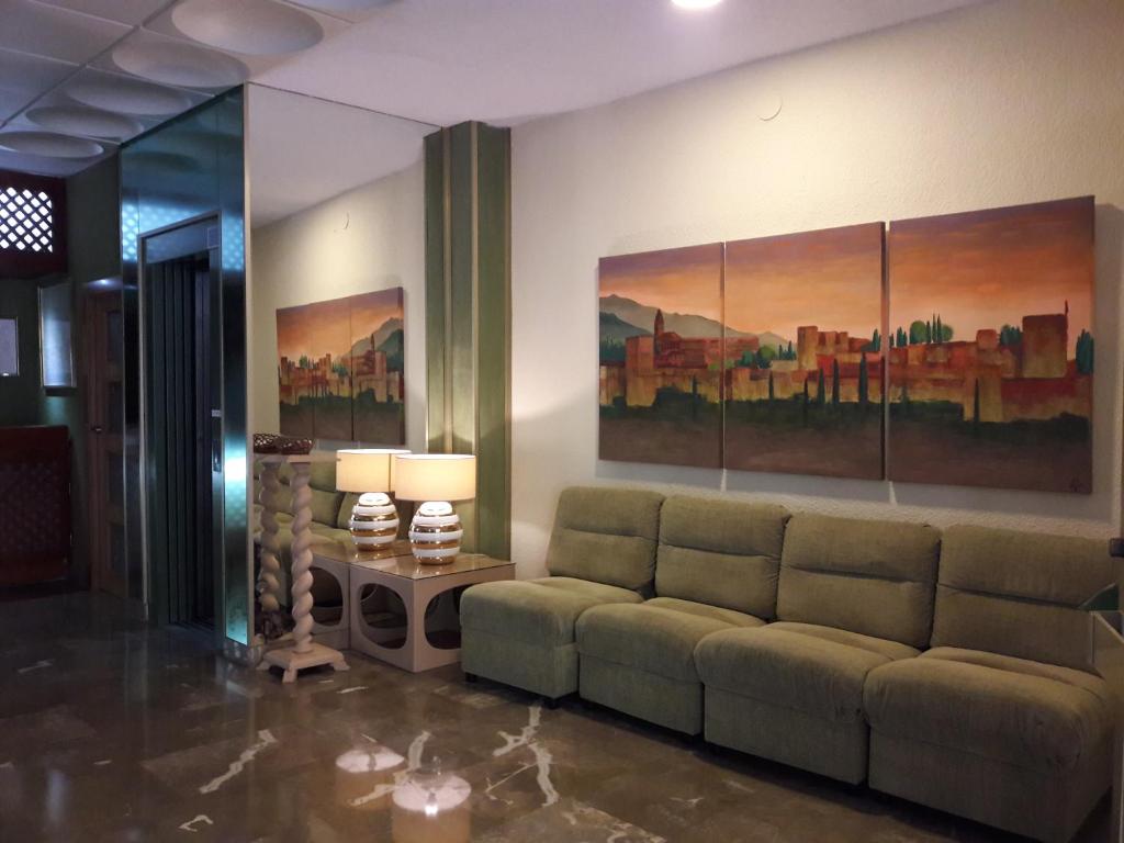 a living room with a couch and paintings on the wall at Hotel Paraíso in Lanjarón