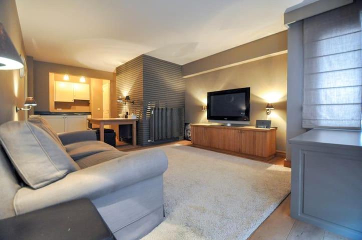ein Wohnzimmer mit einem Sofa und einem Flachbild-TV in der Unterkunft Beverly house in Knokke-Heist